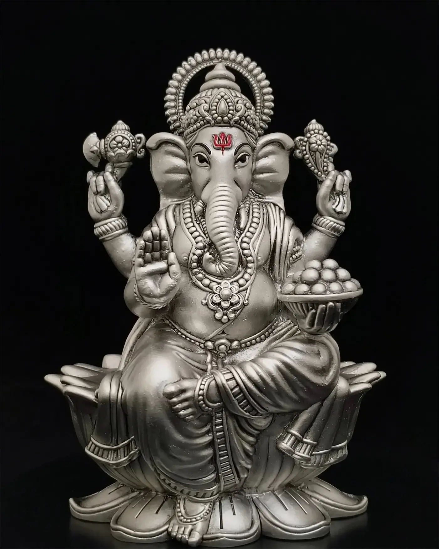 A silver Ganesha, lit on black